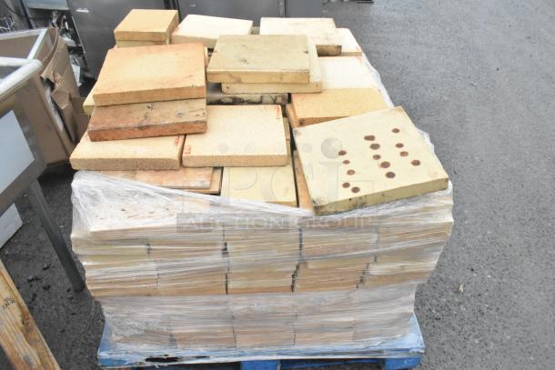 200 cooking stones for pizza ovens, stacked on a pallet, wrapped in plastic. Some stones show wear, varying patterns.
