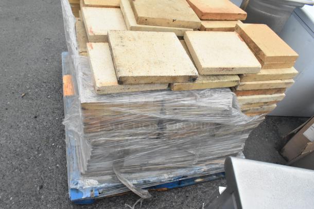 Stack of 200 cooking stones for pizza oven, wrapped and placed on a pallet. Used condition, suitable for high-heat baking.