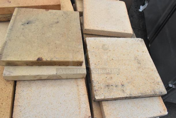 200 pizza oven cooking stones, varying shades, stacked. Includes 200 stones; ideal for high-volume baking. Some wear visible.