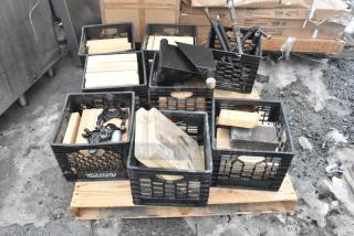 Pallet lot with various items, including cooking stones for pizza oven and black metal legs, in milk crates on wooden pallet.