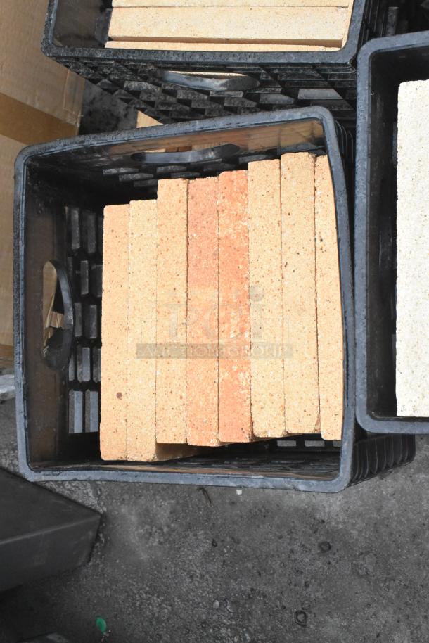 Pallet of cooking stones for pizza ovens, various shapes and sizes, in black crates. Suitable for baking and grilling.