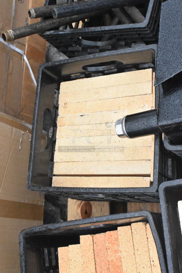 Pallet lot containing multiple cooking stones for pizza ovens and metal legs, stacked in black crates.