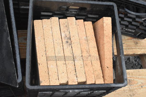 Pallet of cooking stones in a crate, suitable for pizza ovens, with visible minor wear and black plastic containers.