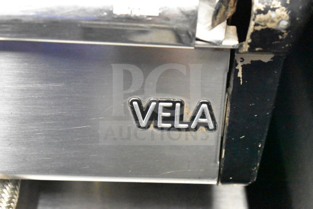 Vela espresso machine with logo. Stainless steel finish, visible wear on trim. Perfect for commercial use.