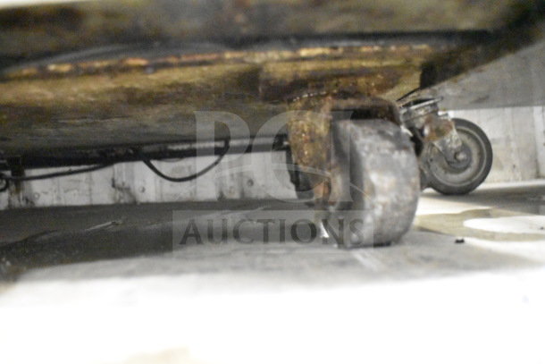 Under view of the True TUC-48 cooler showing commercial casters, visible wear and signs of rust.