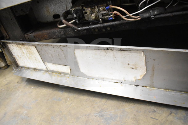 Jade Range commercial gas 6-burner with salamander, showing signs of wear beneath with visible panel markings.