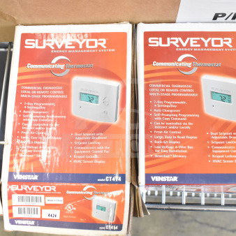 Two new Surveyor CT414 commercial thermostats in boxes, featuring 7-day programmability, dual setpoint, and Internet control.
