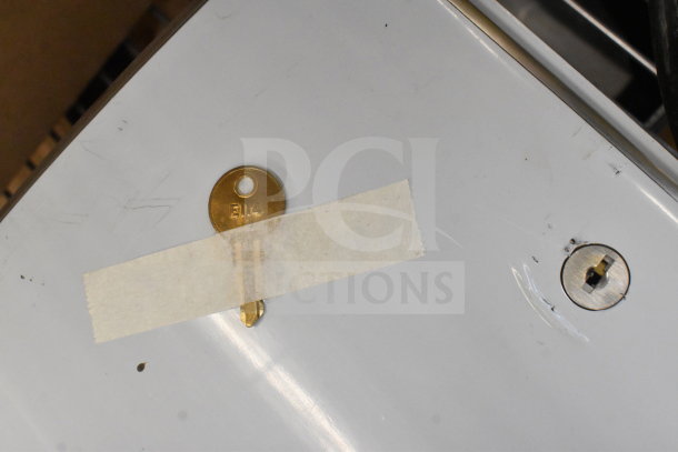 Brand new wall mount unit with visible keyhole and minor scratches, tape holding key marked "EM4;" some dents present.