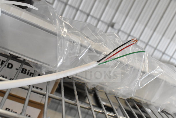 Bartco Lighting light fixture, new, encased in plastic wrap with exposed wiring, resting on a metal shelf.