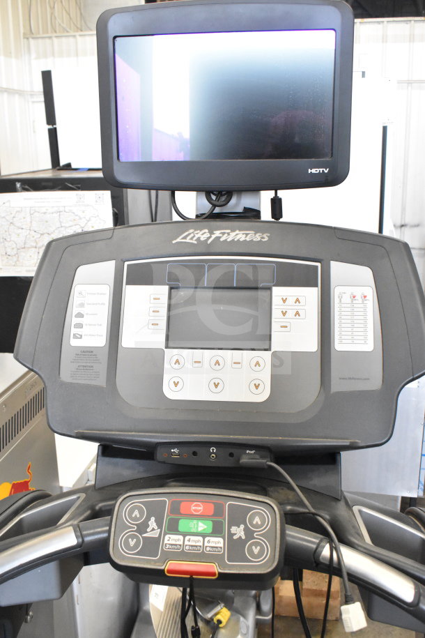 Life Fitness ATV15-XXXA-02 treadmill with monitor. Features control panel, speed settings, iPod dock; good condition.
