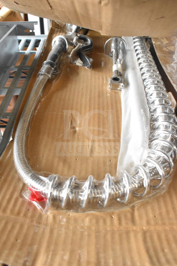 Brand new scratch and dent faucet with handles, packaged on cardboard, visible stainless steel coiled hose.