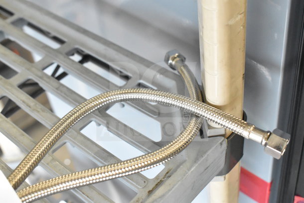 Braided stainless steel hose, new condition, attached to shelving and pipe, features standard connectors.
