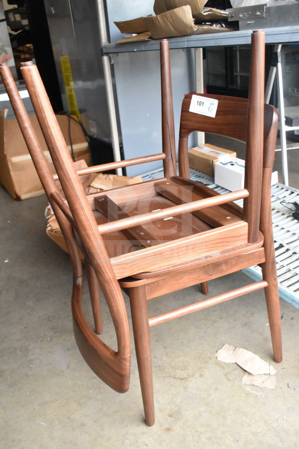 Two wooden dining-height chairs stacked, featuring a smooth finish and sturdy legs. Label reads "101 QTY X2."