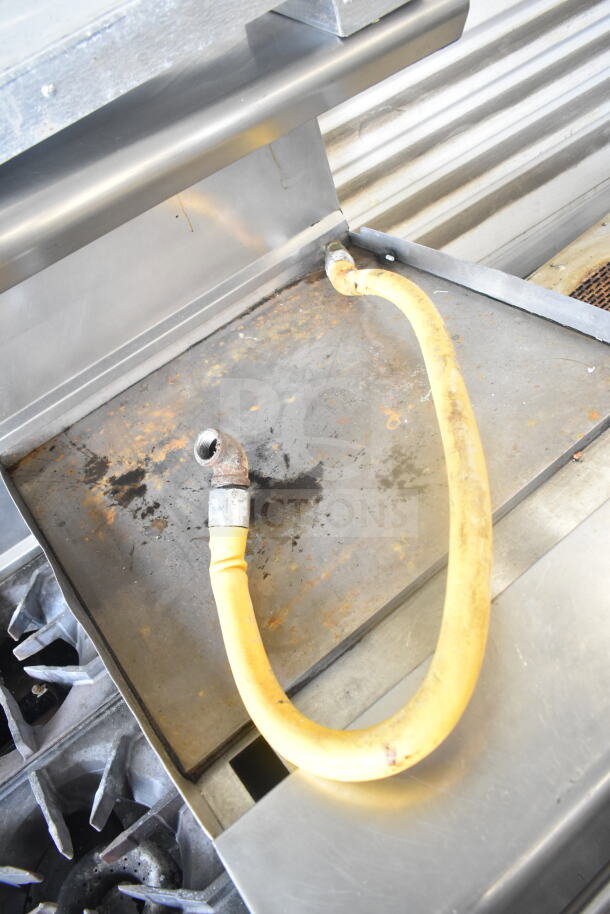 American Range commercial gas range with 6 burners, flat top griddle, 2 ovens, backsplash, and overshelf. Visible wear.