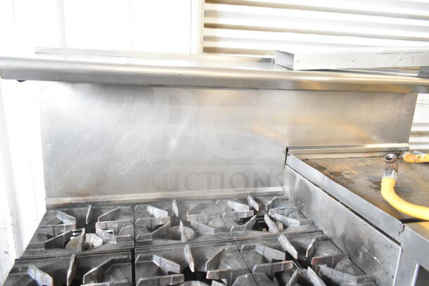 American Range commercial gas range with 6 burners, flat top griddle, 2 ovens, backsplash, and over shelf. Used condition.