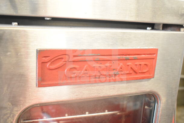 Garland commercial convection oven with view-through doors, thermostatic controls, metal legs, and casters. Logo visible.