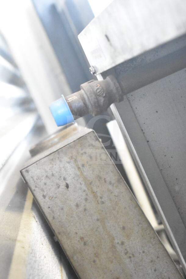 Close-up of a Garland commercial oven's gas connection, featuring a rusted pipe with a blue cap.