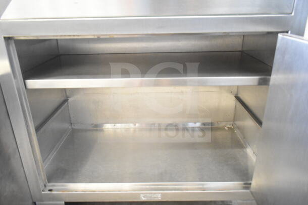 Shampaine Commercial Merchandising Cabinet, stainless steel, two shelves, minor wear, ideal for display and storage.