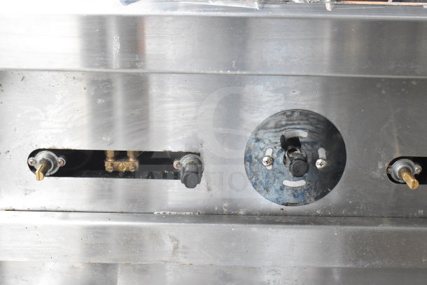 PrecisionHD commercial gas range control panel with knobs and temperature markings. Stainless steel surface shows slight wear.