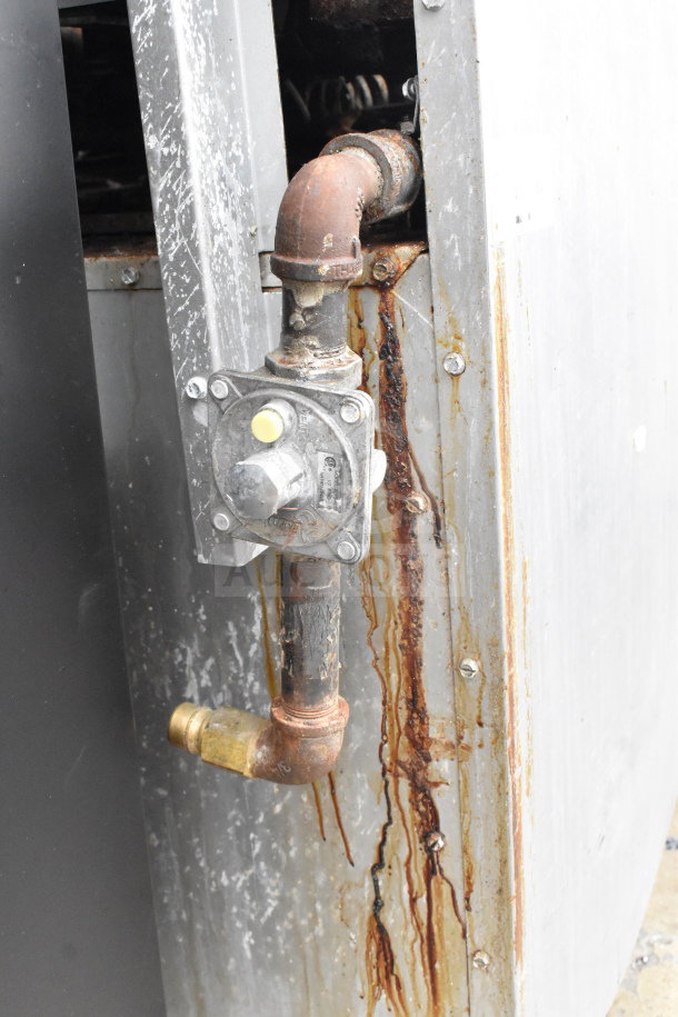 Commercial gas range, PrecisionHD, with visible external plumbing showing corrosion and rust stains.