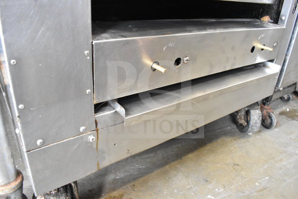 Commercial gas-powered upright 2-deck broiler on casters, stainless steel, visible wear, control knobs intact.