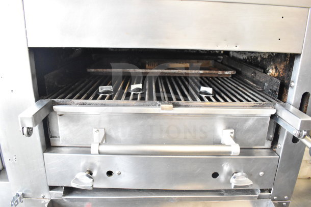 Commercial gas-powered upright 2 deck broiler with grill racks and control knobs, on commercial casters, used condition.