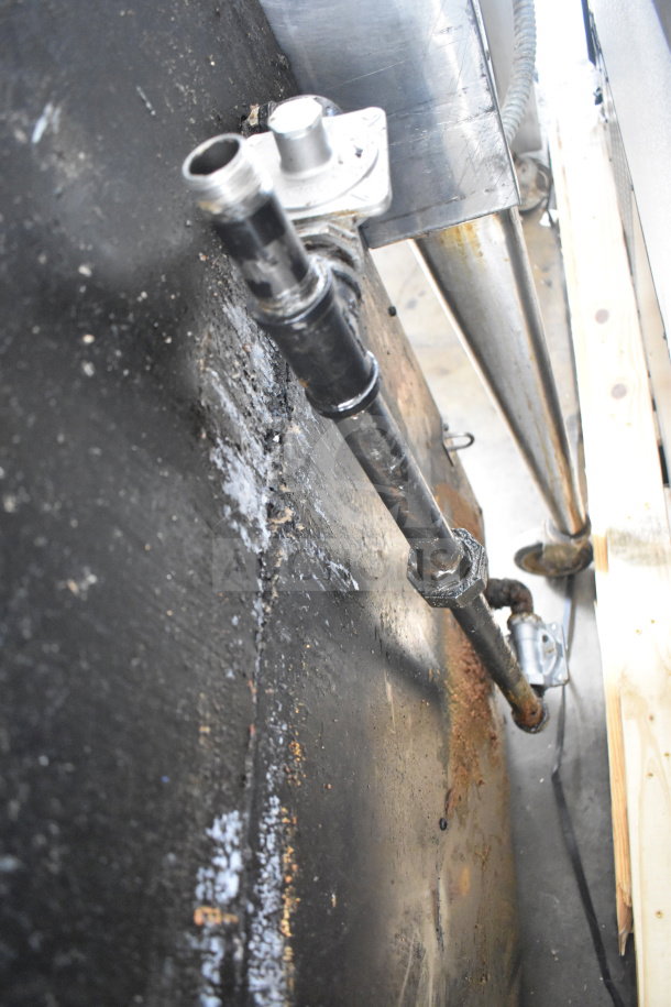 Close-up of gas connection on commercial upright 2-deck broiler, showing pipe and bolts. Dust and residue visible.