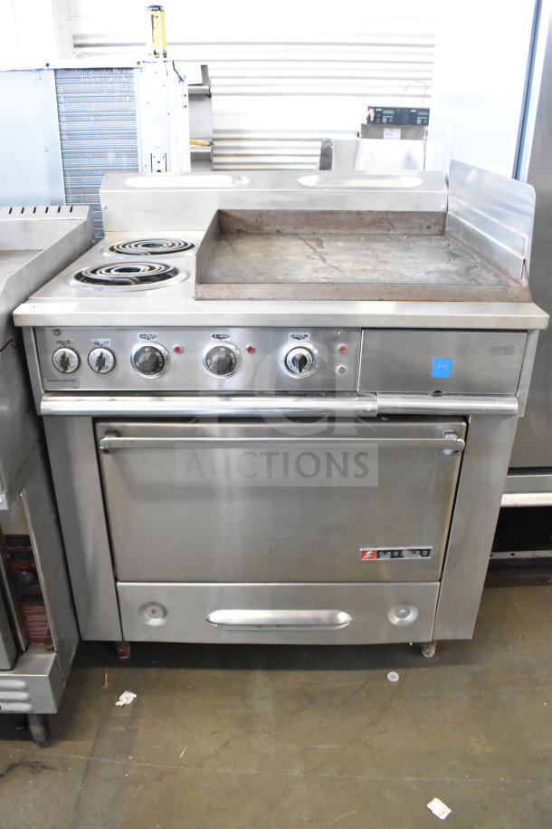 Garland commercial flat top griddle with 2 burners and oven, stainless steel, control knobs, some surface wear, sturdy build.