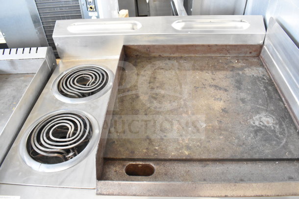 Garland commercial flat top griddle with two burners and oven. Shows used condition with visible wear on the cooking surface.