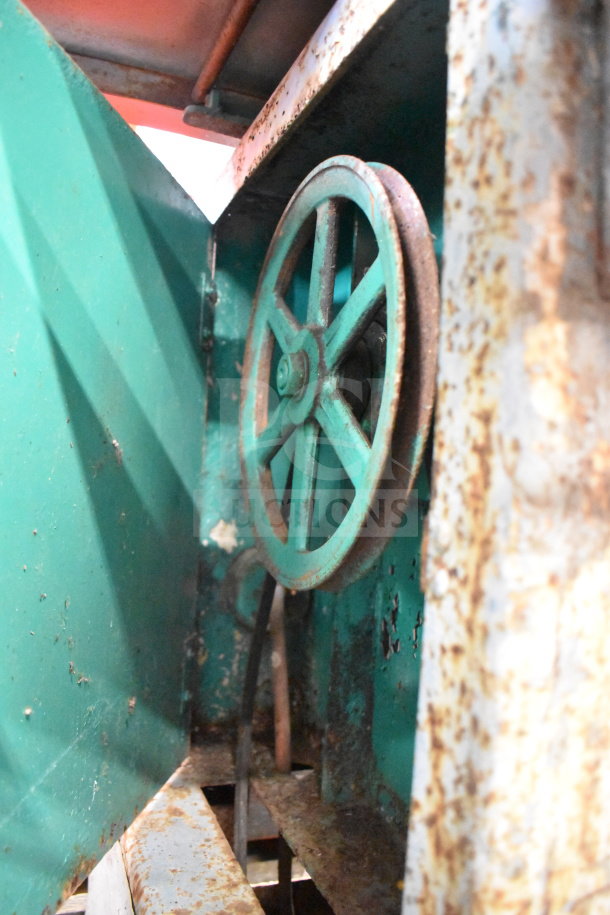 Butcher Boy Commercial Meat Saw, floor style with visible rust and wear, pulley wheel detail, industrial green finish.