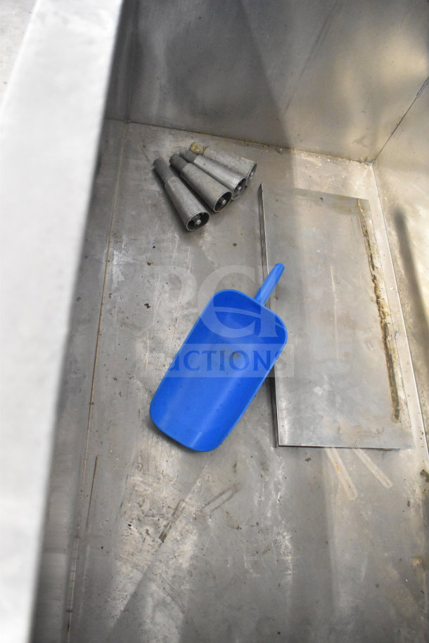 Commercial ice bin with blue scoop and metal components inside; part of Manitowoc QD1002A machine.