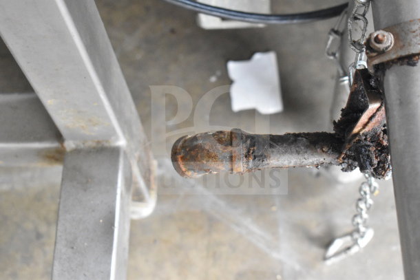 Rusty handle and chain component of a commercial manual tilt braising pan in fair condition, showing signs of wear.