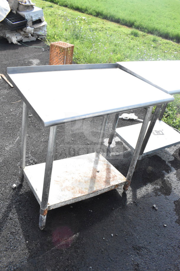 Commercial metal table with under shelf, showing signs of rust and outdoor wear, ideal for heavy-duty use.