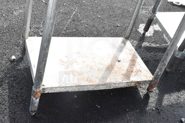 Commercial table with an under-shelf, metal frame, showing wear and rust, solid construction, ideal for industrial use.