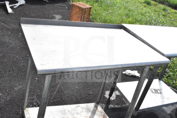 Commercial stainless steel table with an under shelf, used condition, visible markings on surface.