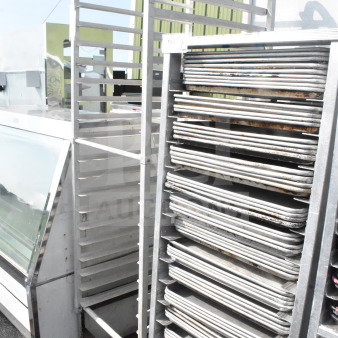 Commercial pan transport rack with multiple shelves and sturdy casters, suitable for bakery use.