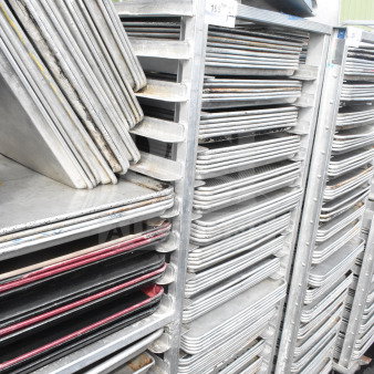 Commercial pan transport rack with 70 baking pans on casters. Sturdy metal frame, visible wear on pans.