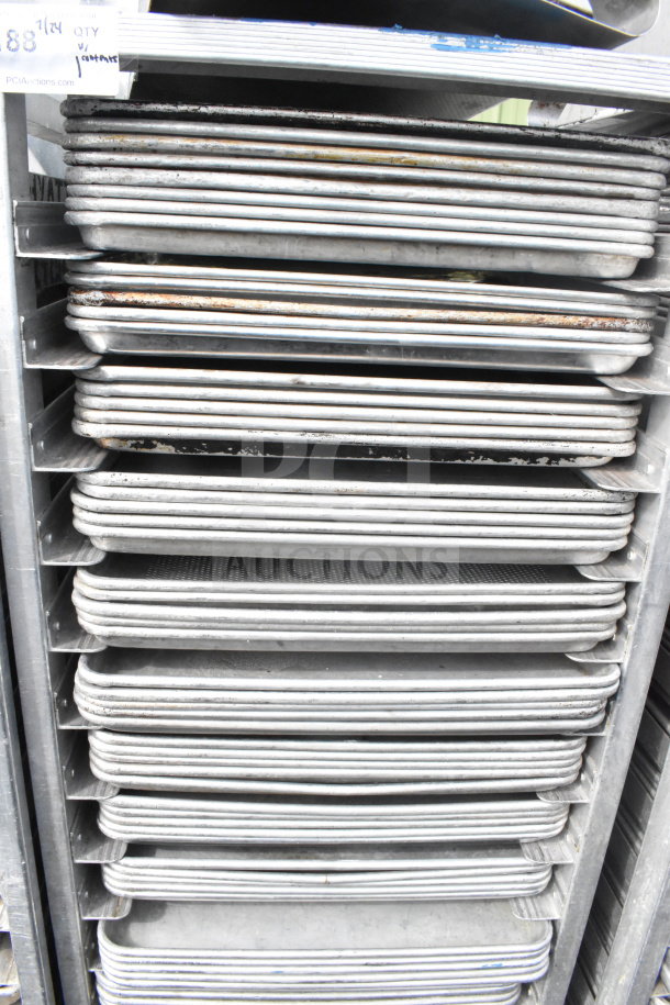 Commercial pan transport rack with 70 aluminum baking pans on casters. Some pans show signs of use. Auction tag visible.