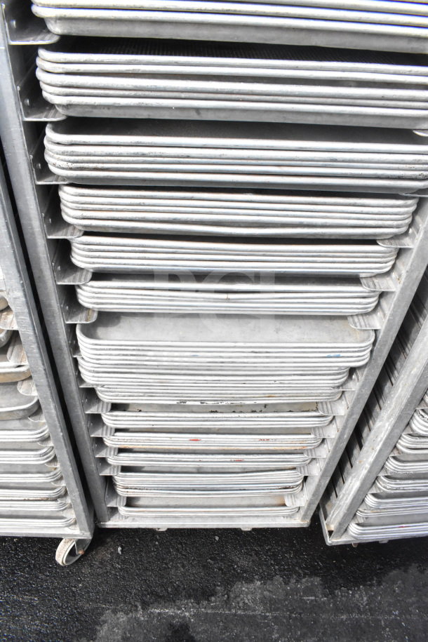 Commercial pan transport rack with 70 baking pans on heavy-duty casters, in used condition. Ideal for bakeries.