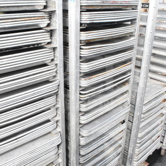 Commercial pan transport rack with 70 baking pans on casters, durable metal, used condition, ideal for baking industry.