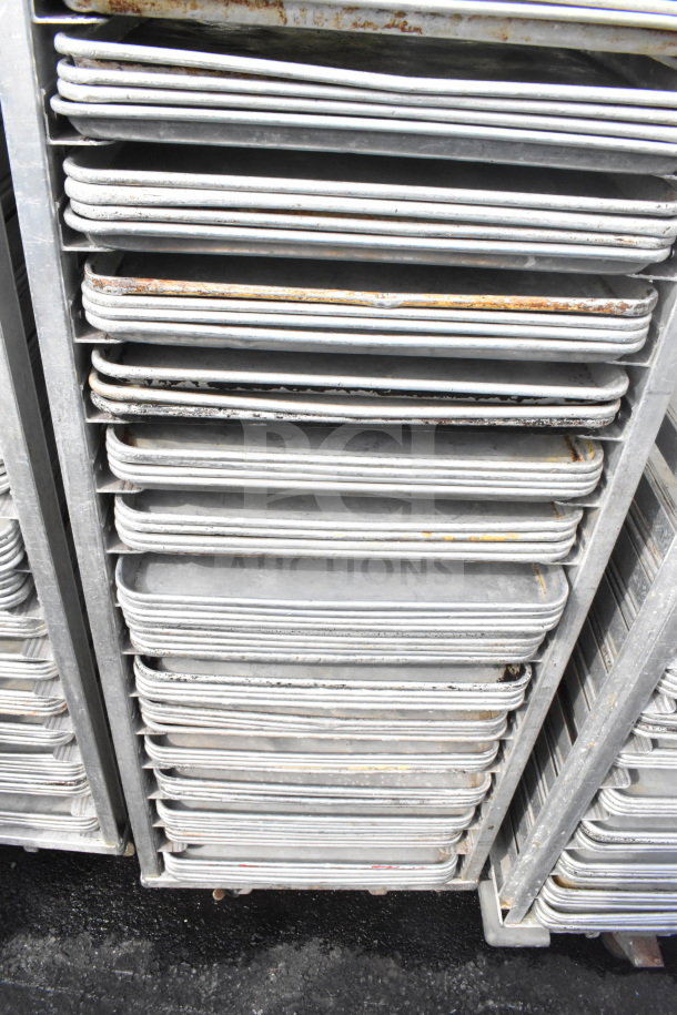 Commercial pan transport rack with 70 baking pans, on sturdy commercial casters. Some signs of wear.