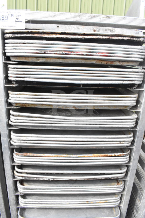 Commercial pan transport rack with 70 baking pans on casters. Visible wear on pans. Auction tag indicates item number 489.