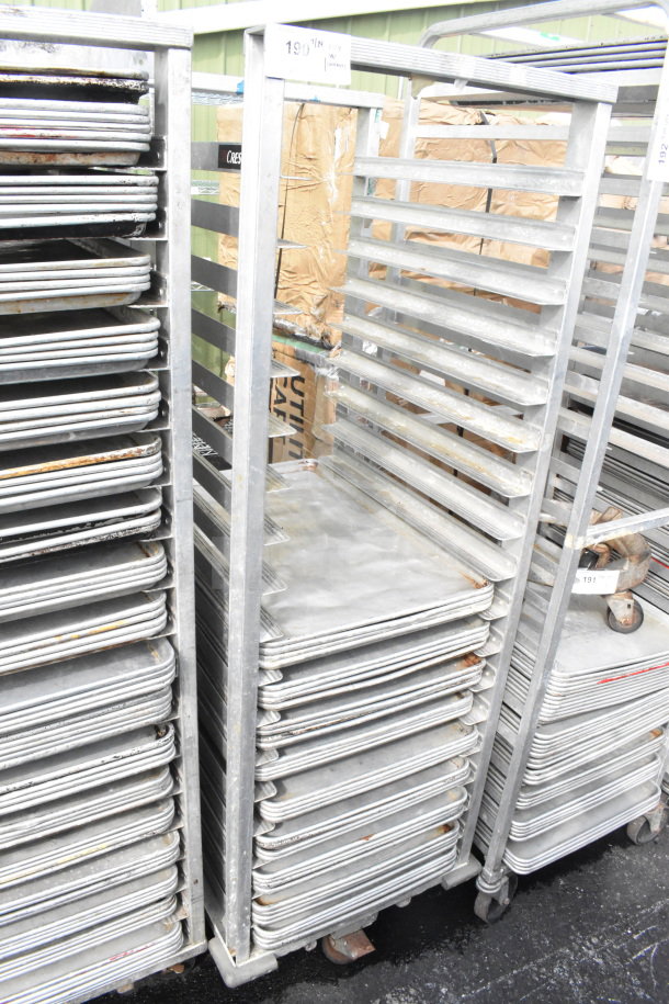 Commercial pan transport rack with 36 baking pans on casters. Shows signs of wear, ideal for bakery use.