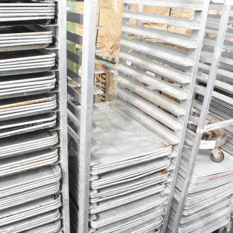 Commercial pan transport rack with 36 baking pans on casters. Shows signs of wear, ideal for bakery use.