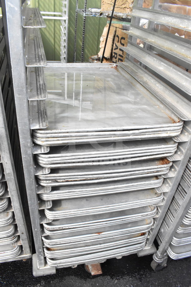 Commercial pan transport rack with 36 baking pans on commercial casters, showing signs of wear and rust.