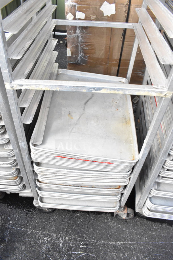 Commercial pan transport rack with 40 baking pans, sturdy metal frame on commercial casters, showing some signs of use.