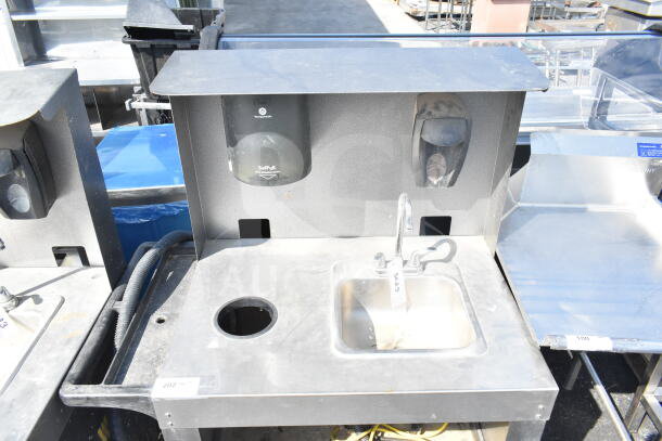 Commercial portable sink with stainless steel top, integrated faucet, and soap dispensers. Features sturdy casters for mobility.