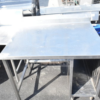 Stainless steel commercial table with backsplash, open lower shelf, sturdy legs, minimal wear. Ideal for kitchen use.