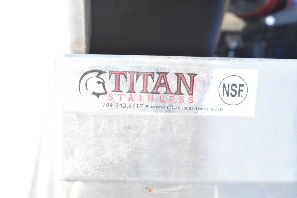 Titan Stainless commercial table, NSF certified, in good condition. Features stainless steel surface with logo and contact details visible.