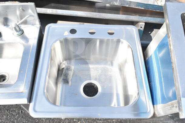 Two stainless steel single bay sinks, drop-in style, with pre-drilled holes. Slight wear visible.
